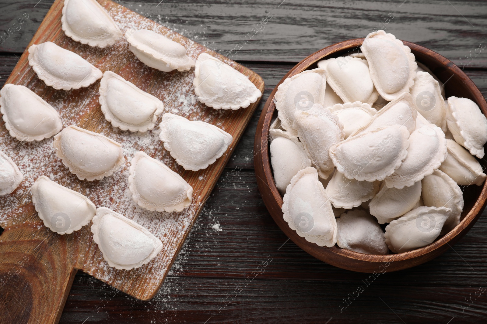 Photo of Raw dumplings (varenyky) on brown wooden table, flat lay