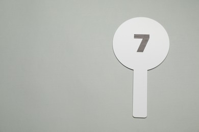 Auction paddle with number 7 on light grey background, top view. Space for text