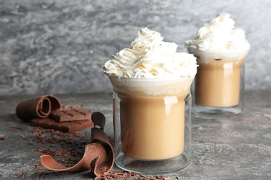 Photo of Glass cups of tasty coffee with whipped cream on gray table