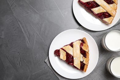 Photo of Slices of delicious fresh cherry pie served on grey table, flat lay. Space for text