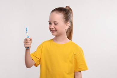 Photo of Happy girl holding toothbrush on white background