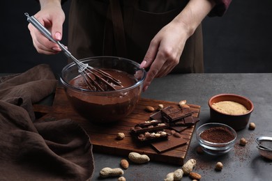 Woman with whisk mixing delicious chocolate cream at table, closeup