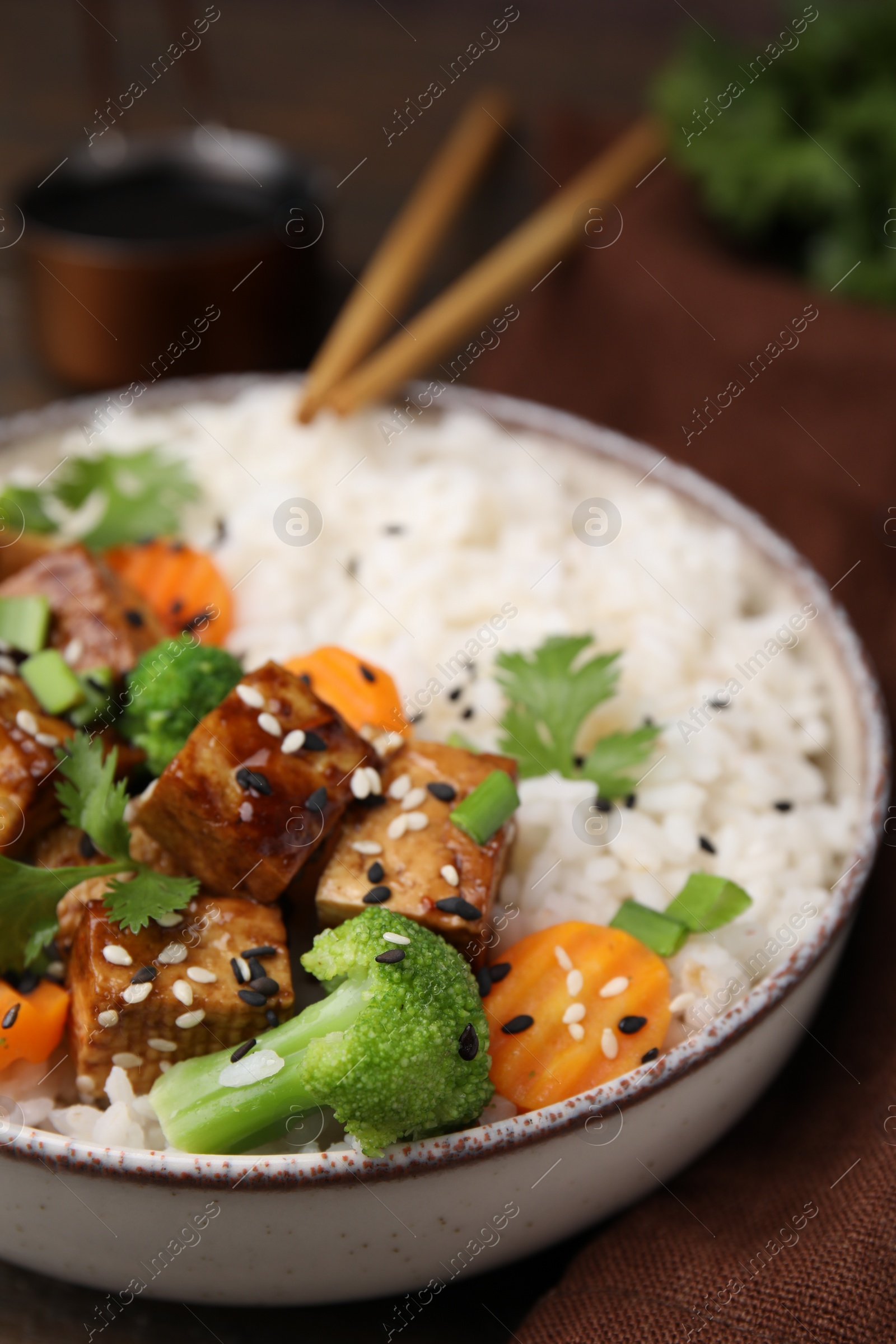 Photo of Bowl of rice with fried tofu, broccoli and carrots on table, closeup