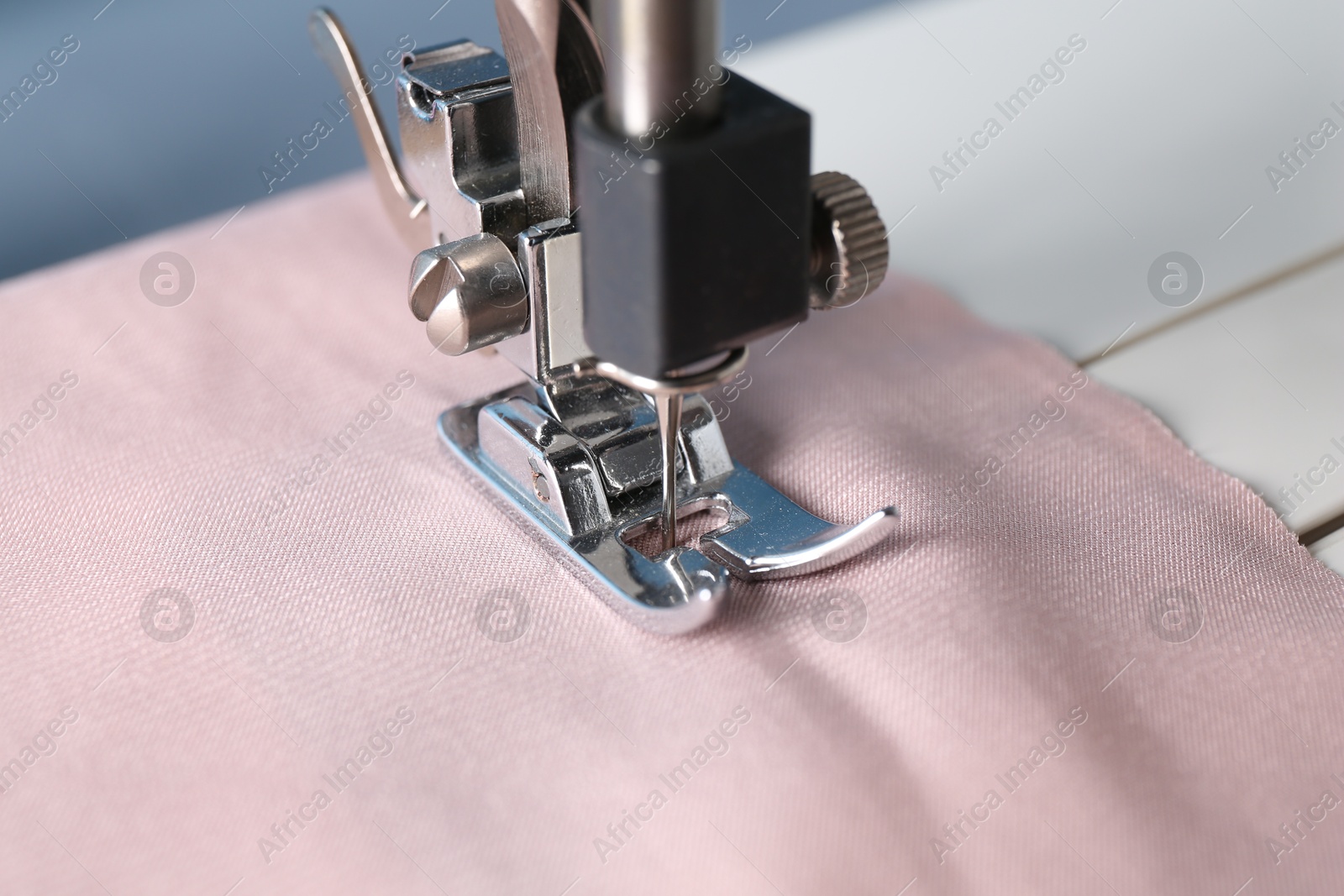 Photo of Sewing machine with color fabric on light background, closeup