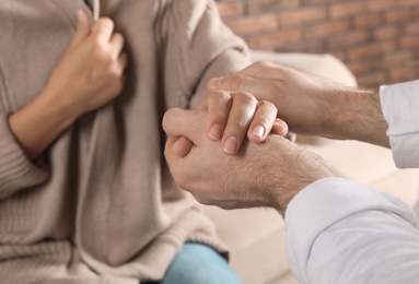 Photo of Man holding woman's hand indoors, closeup. Concept of support and help