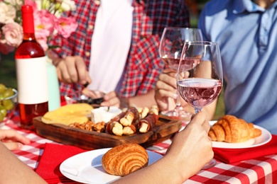 Photo of Group of people having picnic at table outdoors, closeup