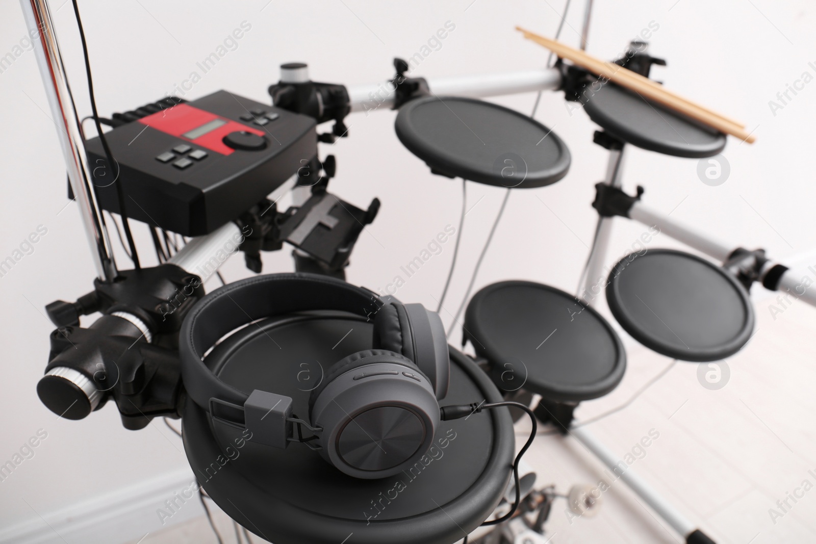 Photo of Modern electronic drum kit with headphones indoors. Musical instrument