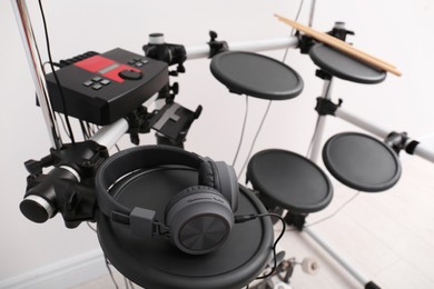 Photo of Modern electronic drum kit with headphones indoors. Musical instrument