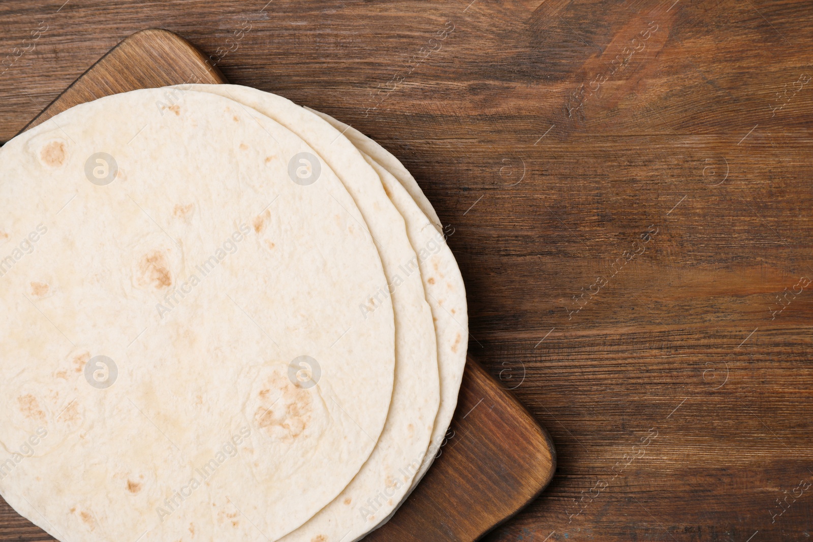 Photo of Board with corn tortillas and space for text on wooden background, top view. Unleavened bread