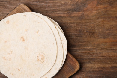 Board with corn tortillas and space for text on wooden background, top view. Unleavened bread
