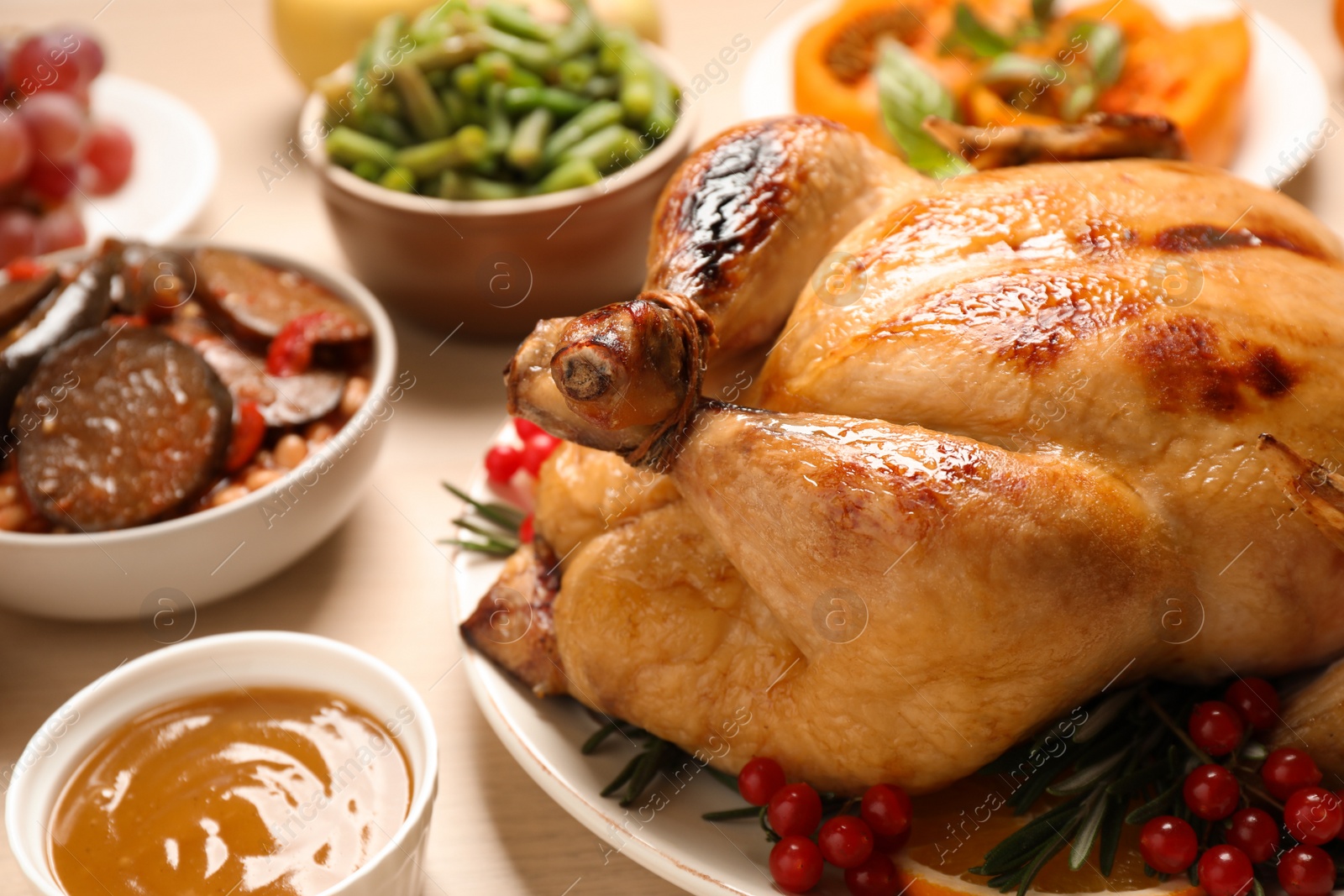 Photo of Traditional Thanksgiving day feast with delicious cooked turkey and other seasonal dishes served on wooden table, closeup