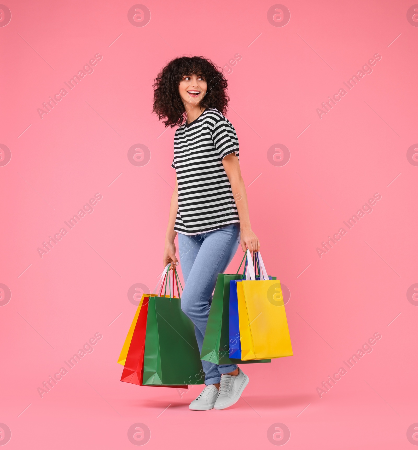 Photo of Happy young woman with shopping bags on pink background