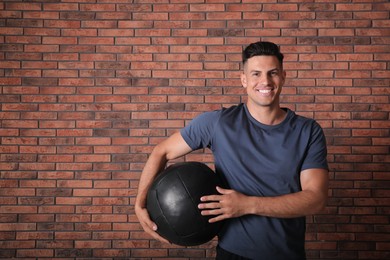 Photo of Athletic man with medicine ball near red brick wall
