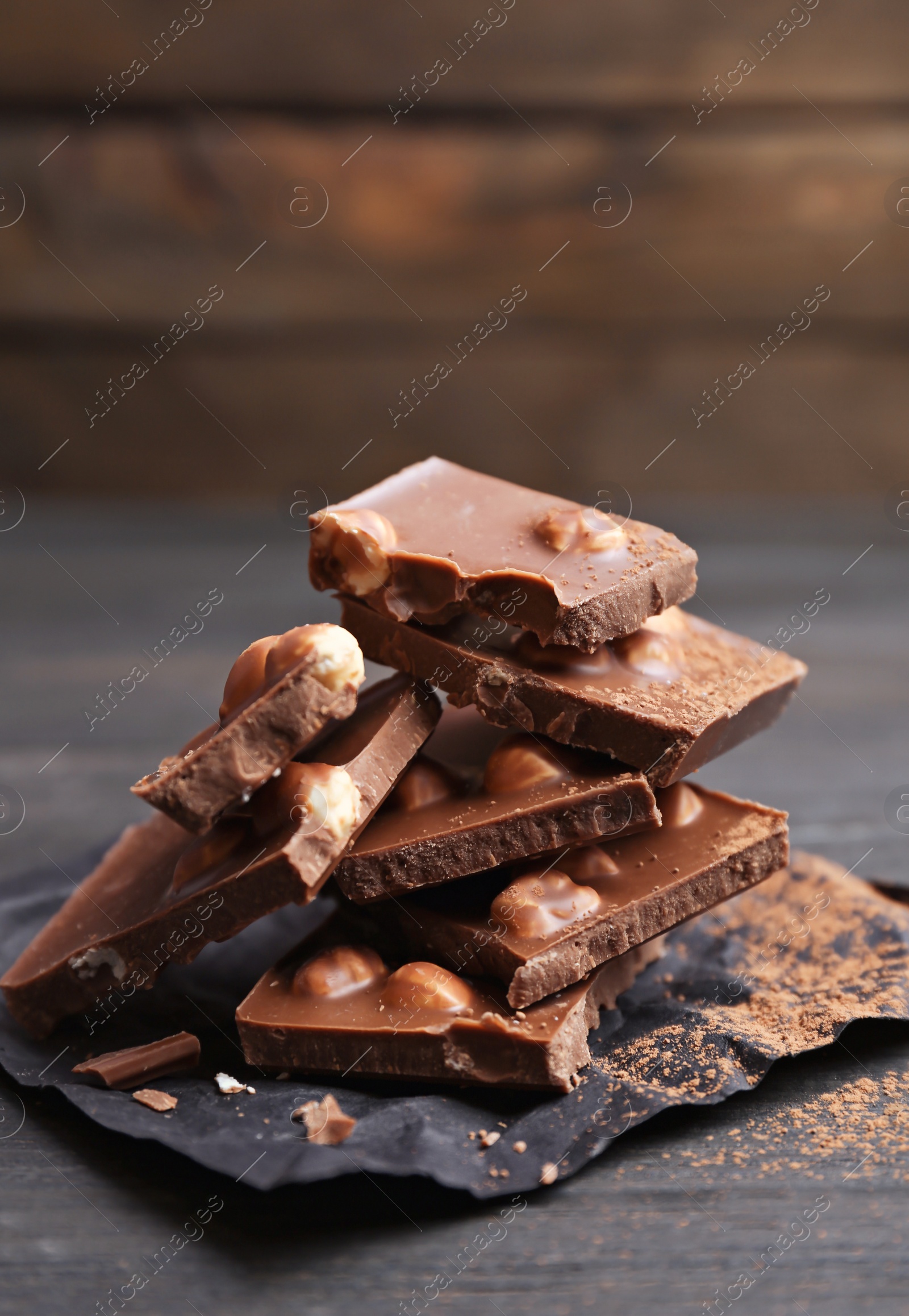 Photo of Yummy chocolate pieces with hazelnuts on wooden table