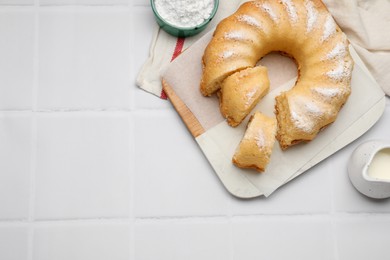 Photo of Delicious sponge cake served on white tiled table, flat lay. Space for text