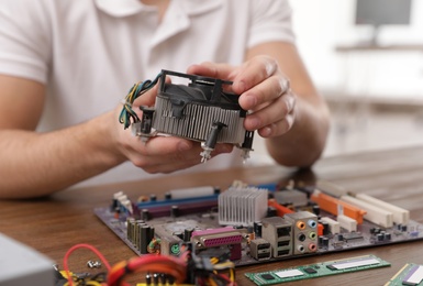 Photo of Male technician repairing computer fan at table, closeup