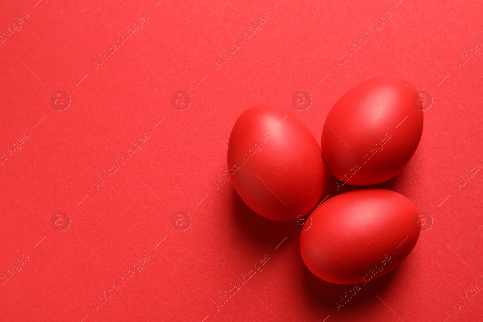 Photo of Flat lay composition of red dyed Easter eggs on color, space for text