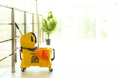 Photo of Mop bucket with cleaning supplies, indoors