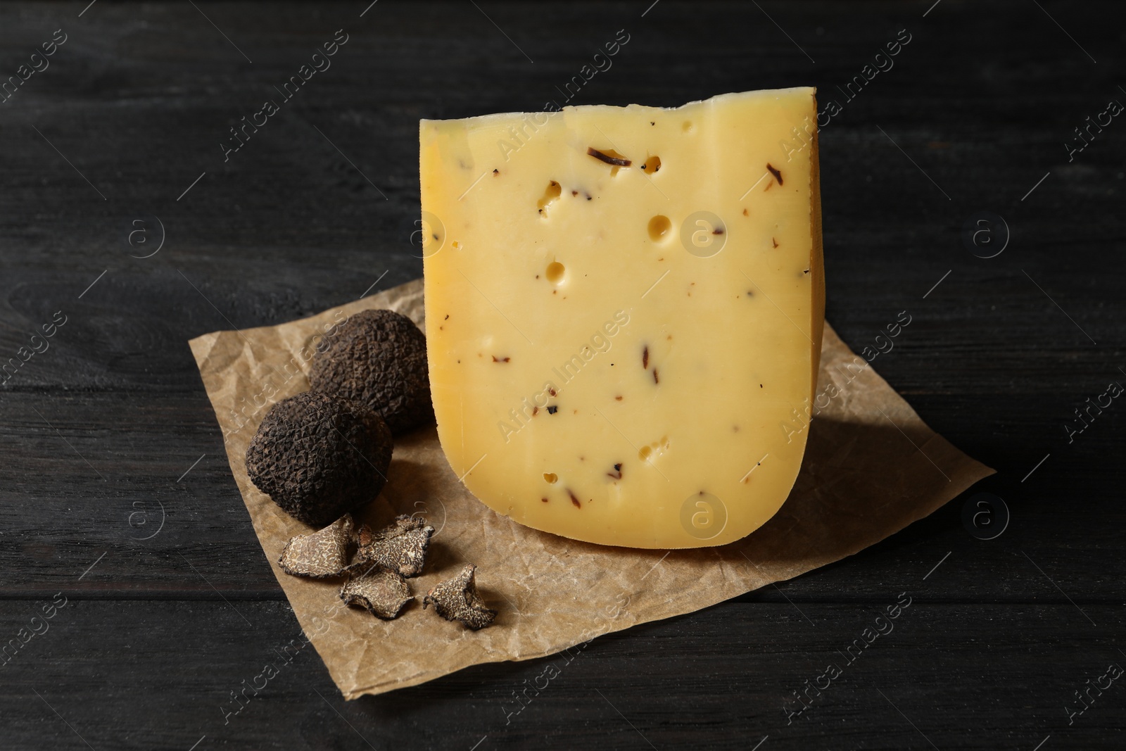 Photo of Delicious cheese and fresh truffles on black wooden table
