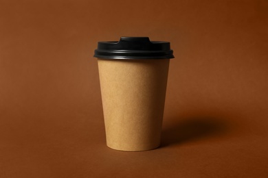 Photo of Takeaway paper coffee cup on brown background, closeup