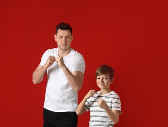Photo of Portrait of sporty dad and his son on color background