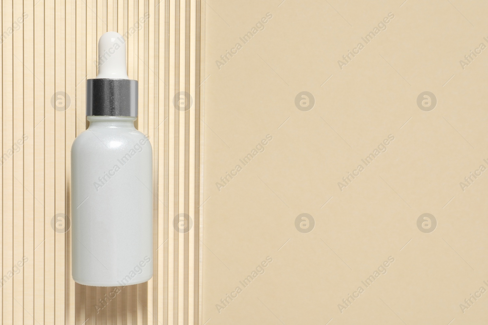 Photo of Bottle of cosmetic serum on beige background, top view. Space for text