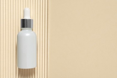 Photo of Bottle of cosmetic serum on beige background, top view. Space for text