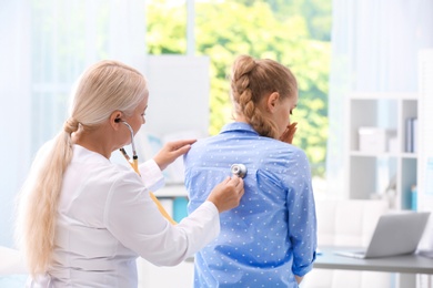 Photo of Doctor examining coughing young woman at clinic