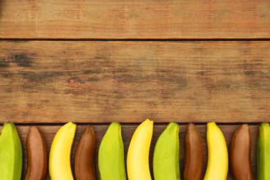 Photo of Many different bananas on wooden table, flat lay. Space for text