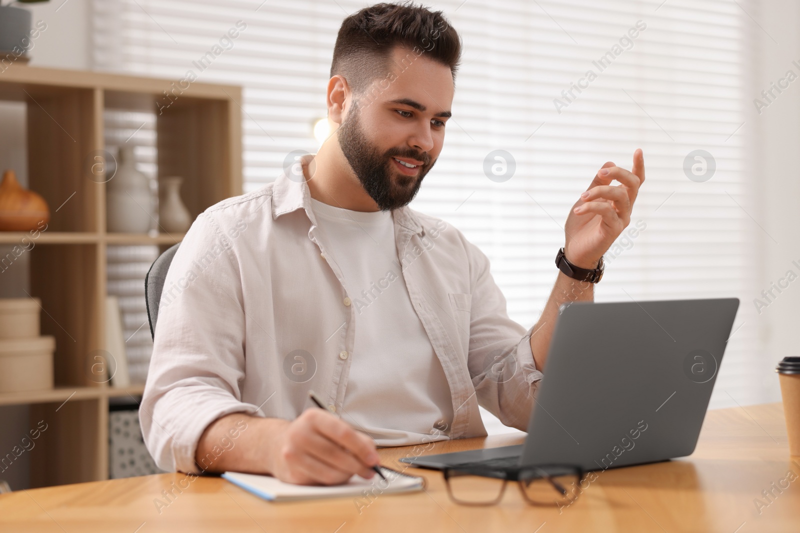 Photo of Young man using video chat during webinar at table in room