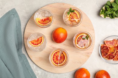 Photo of Delicious refreshing drink with sicilian orange on light grey marble table, flat lay