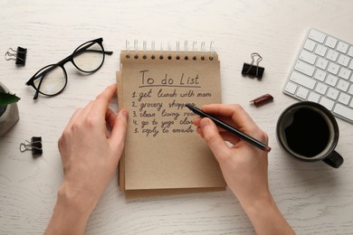 Photo of Woman checking to do list at wooden table, top view