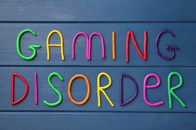 Photo of Phrase Gaming Disorder made of colorful plasticine on blue wooden table, top view