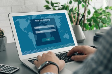 Image of Man using online banking application on laptop at grey table, closeup