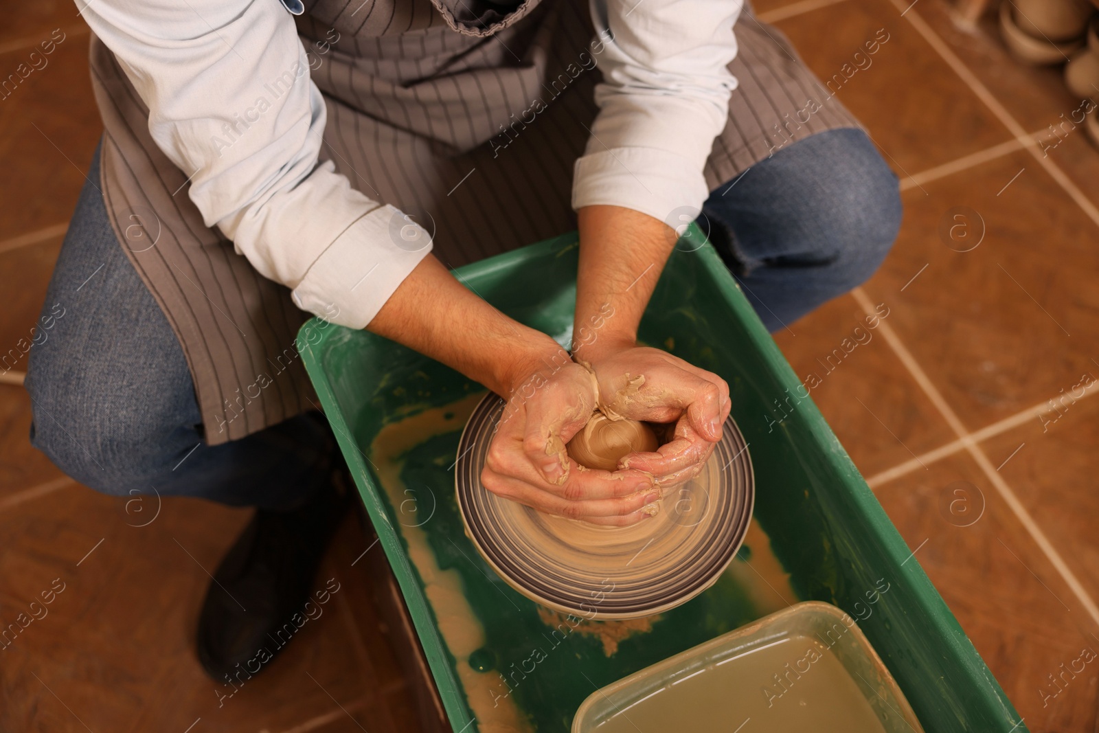 Photo of Man crafting with clay on potter's wheel indoors, closeup