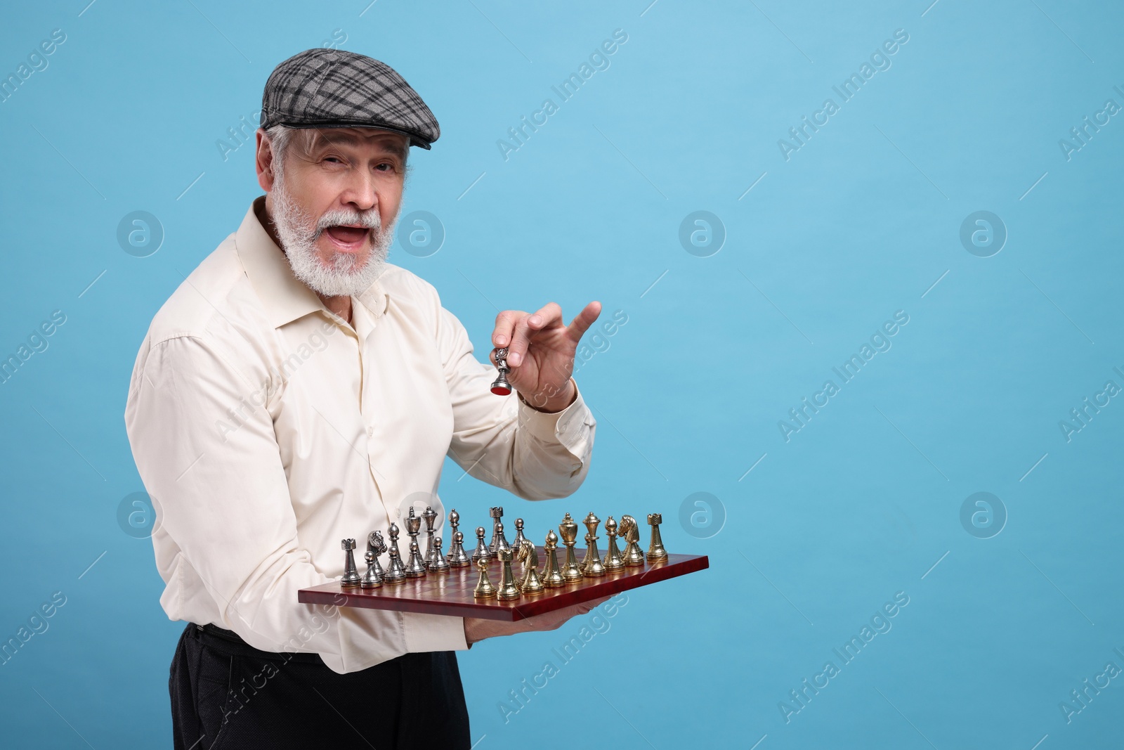Photo of Emotional man with chessboard and game pieces on light blue background. Space for text