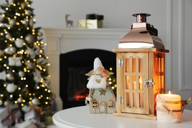 Photo of Beautiful wooden lantern and other decorations on table in room with Christmas tree