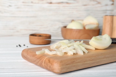 Photo of Wooden board with cut onion on table, closeup