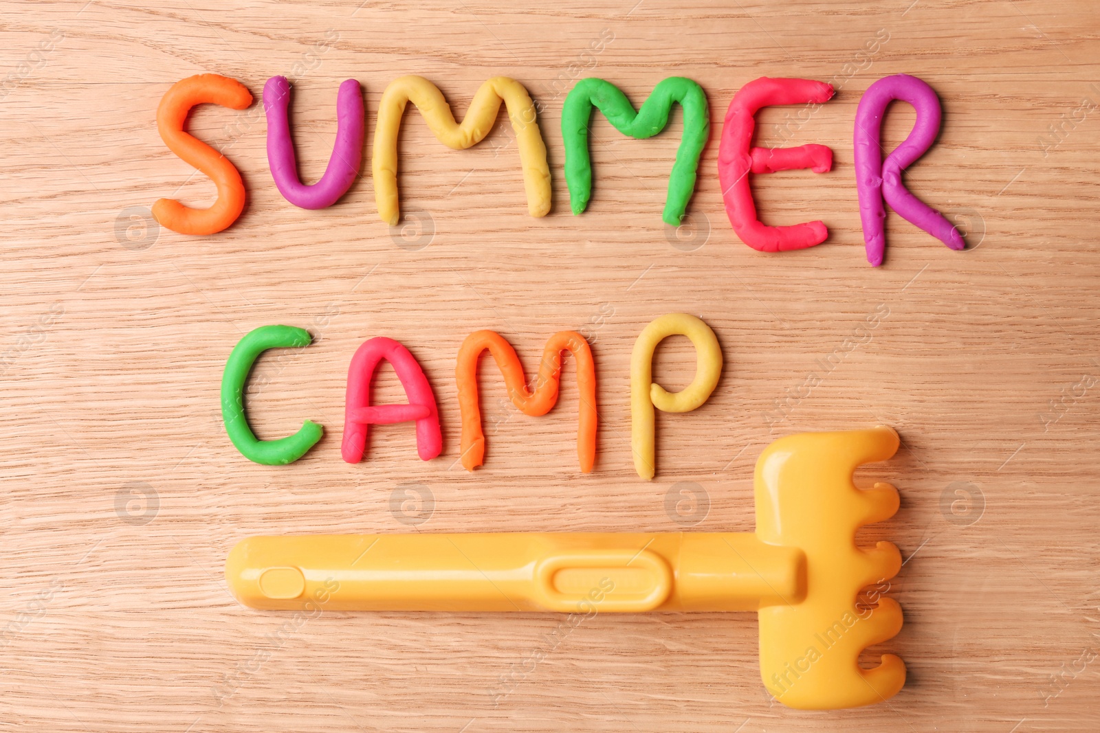 Photo of Text SUMMER CAMP made with play dough on wooden background, top view