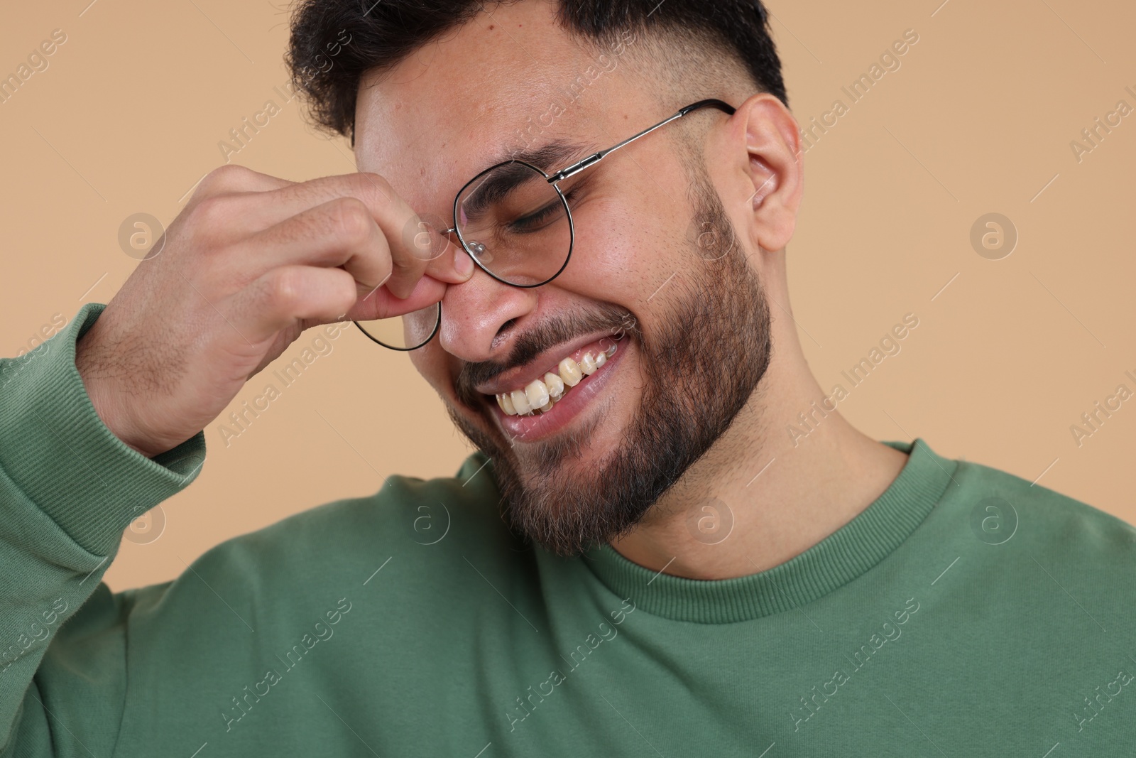 Photo of Handsome young man laughing on beige background, closeup