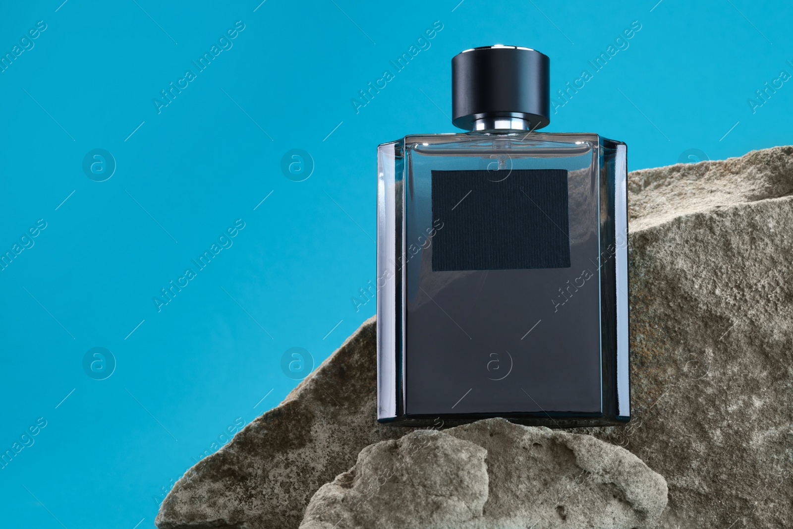 Photo of Stylish presentation of luxury men`s perfume on stones against light blue background. Space for text