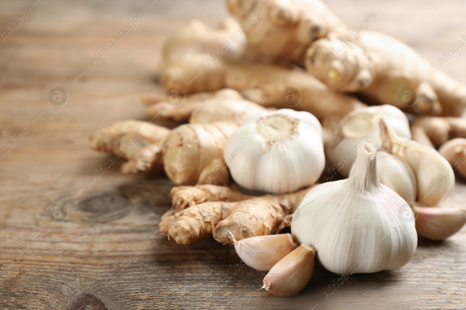 Photo of Ginger and fresh garlic on wooden table, closeup. Natural cold remedies