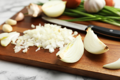 Photo of Board with cut onion and garlic on table, closeup