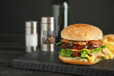 Photo of Tasty burger with bacon on board. Space for text