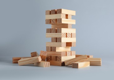 Photo of Jenga tower made of wooden blocks on grey background