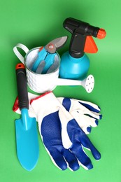 Photo of Gardening gloves, tools and watering can on green background