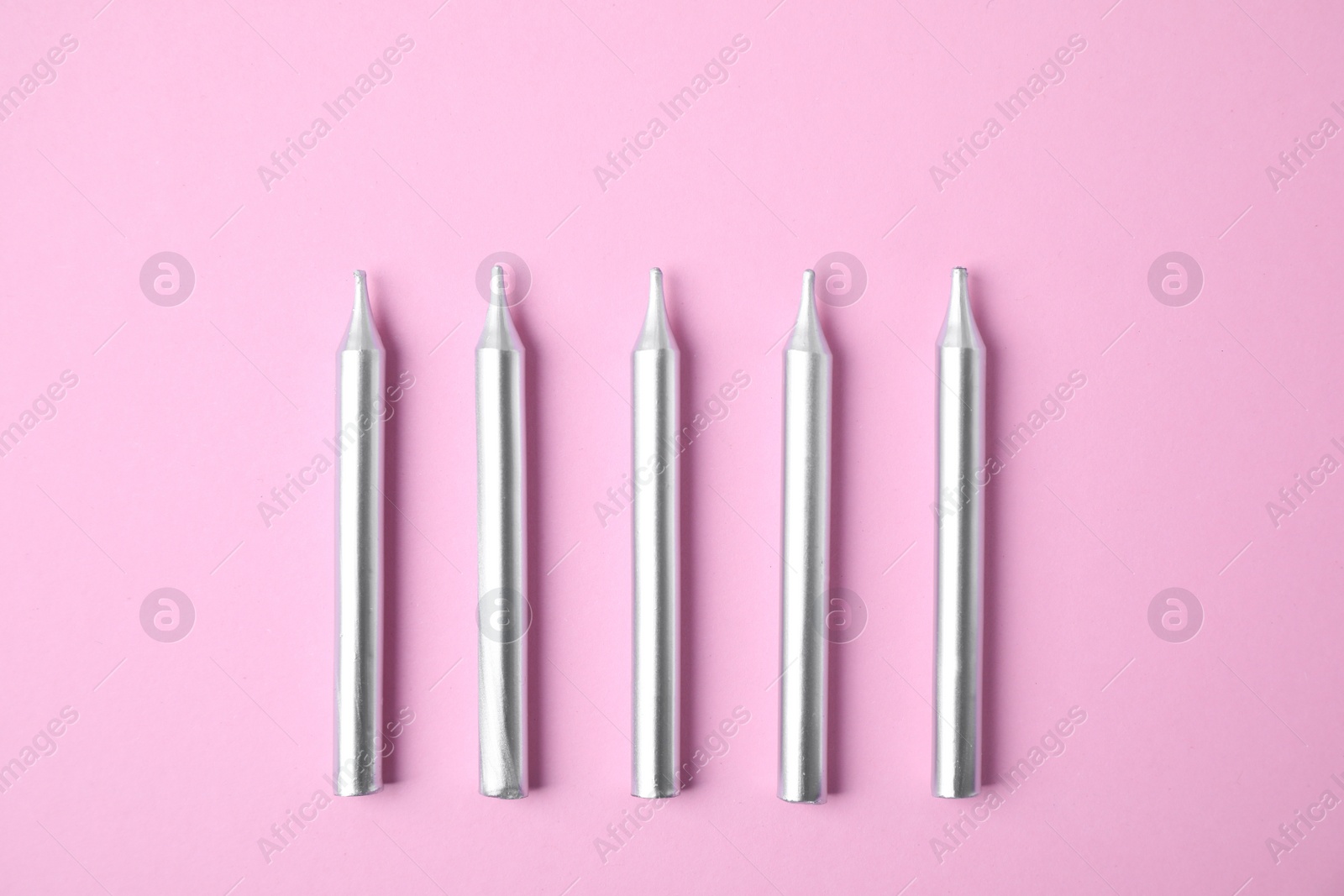 Photo of Silver birthday candles on pink background, top view