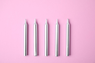 Photo of Silver birthday candles on pink background, top view