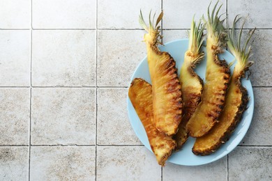 Tasty grilled pineapples on light gray tiled table, top view. Space for text