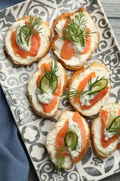 Photo of Tasty canapes with salmon, cucumber, cream cheese and dill on table, top view